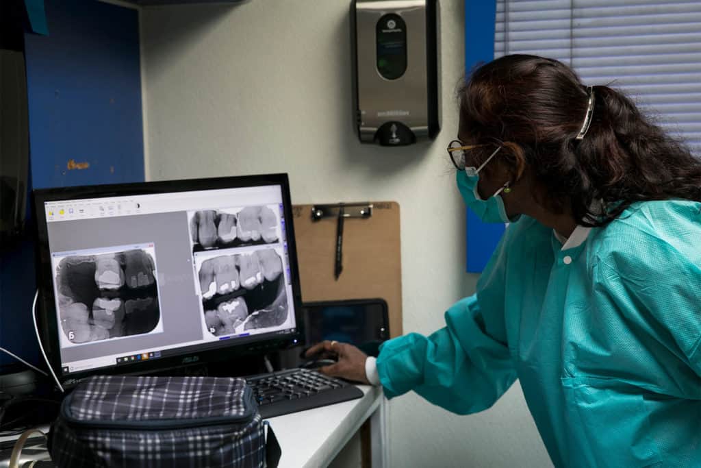 Dental Assistant Anu Rao reviews a patient's X-rays in the mobile unit at the Brazoria County Dream Center in Clute, TX. Americares supported the mobile clinic that provided medical services, including dental screenings, to patients at the center on July 19. Photo by Annie Mulligan